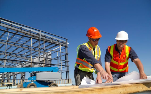Two construction architects review plans at a construction site.